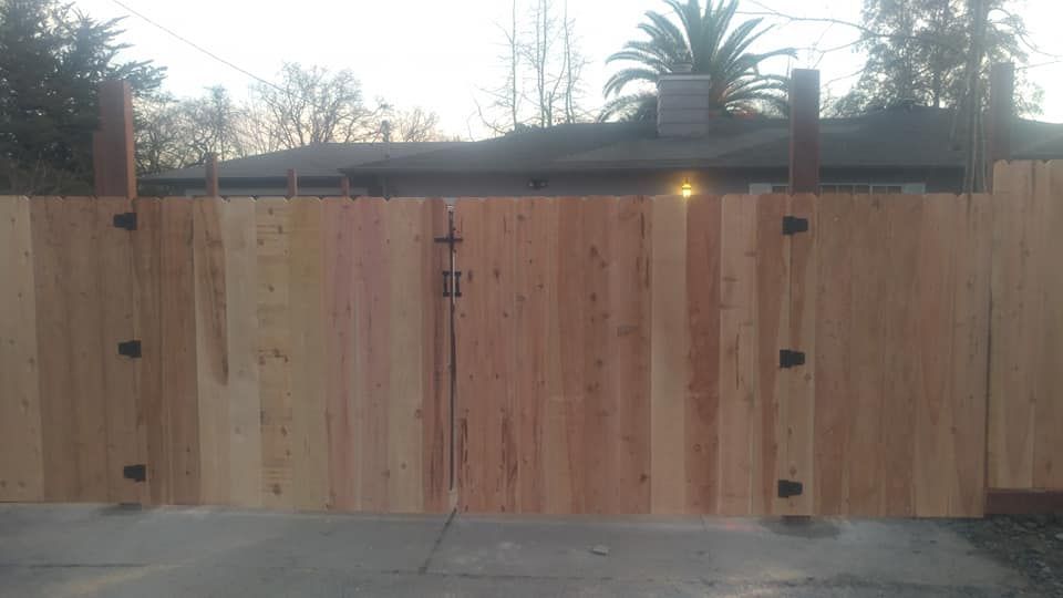 A wooden fence with a gate in front of a house.