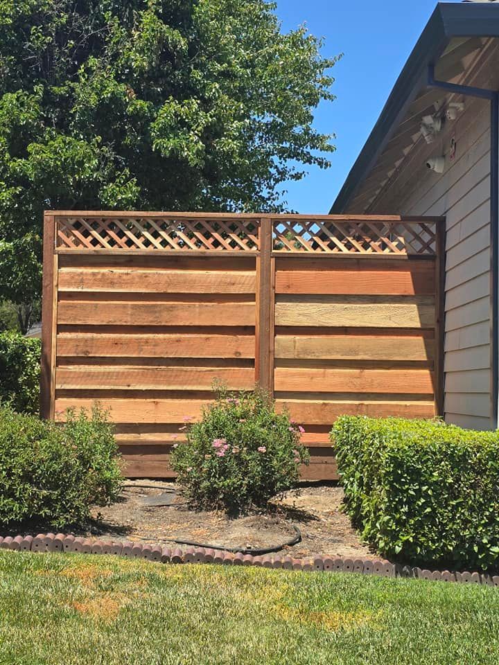 A wooden fence is in the backyard of a house.
