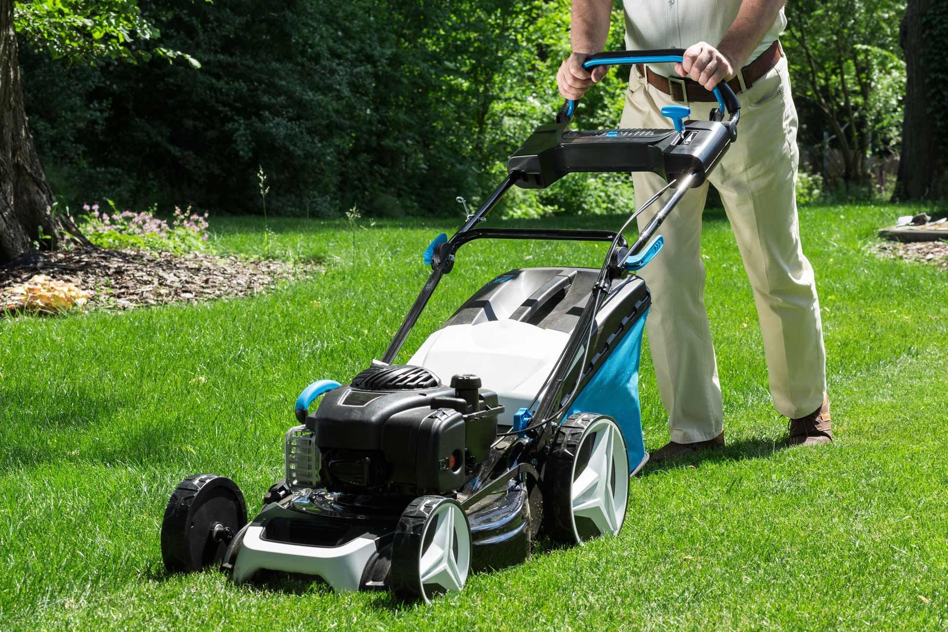 A man is pushing a lawn mower on a lush green lawn