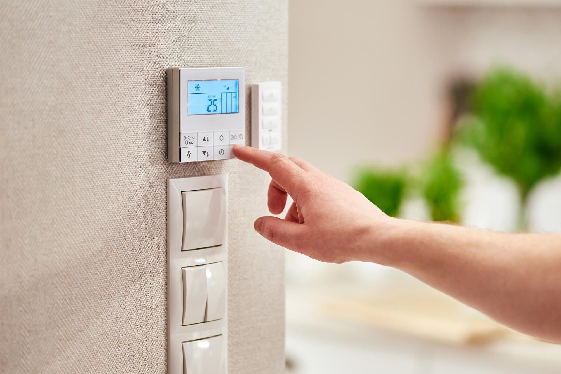 A person is adjusting a thermostat on a wall