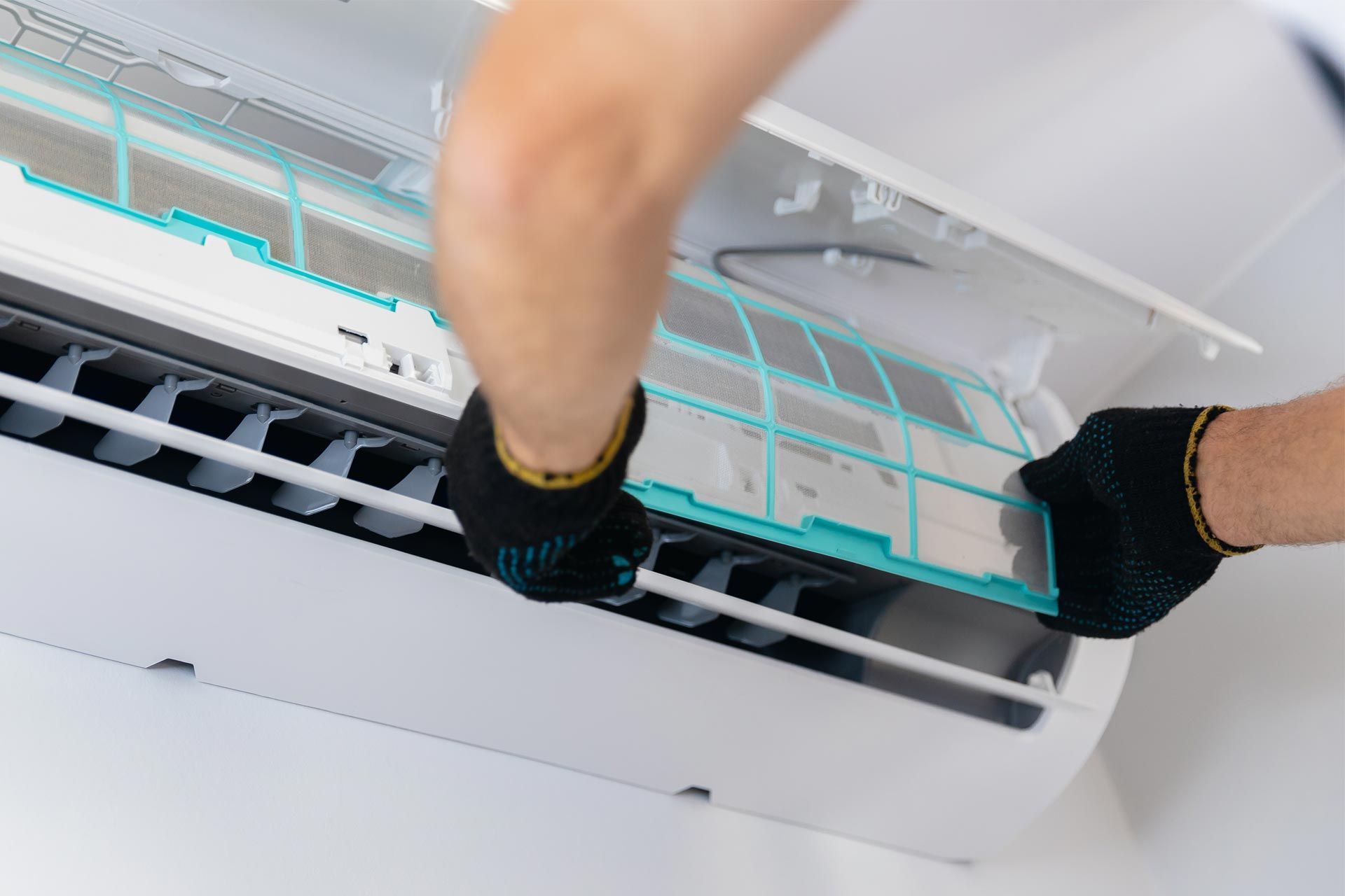 A person is cleaning an air conditioner with gloves