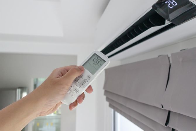 A person is using a remote control to turn on an air conditioner