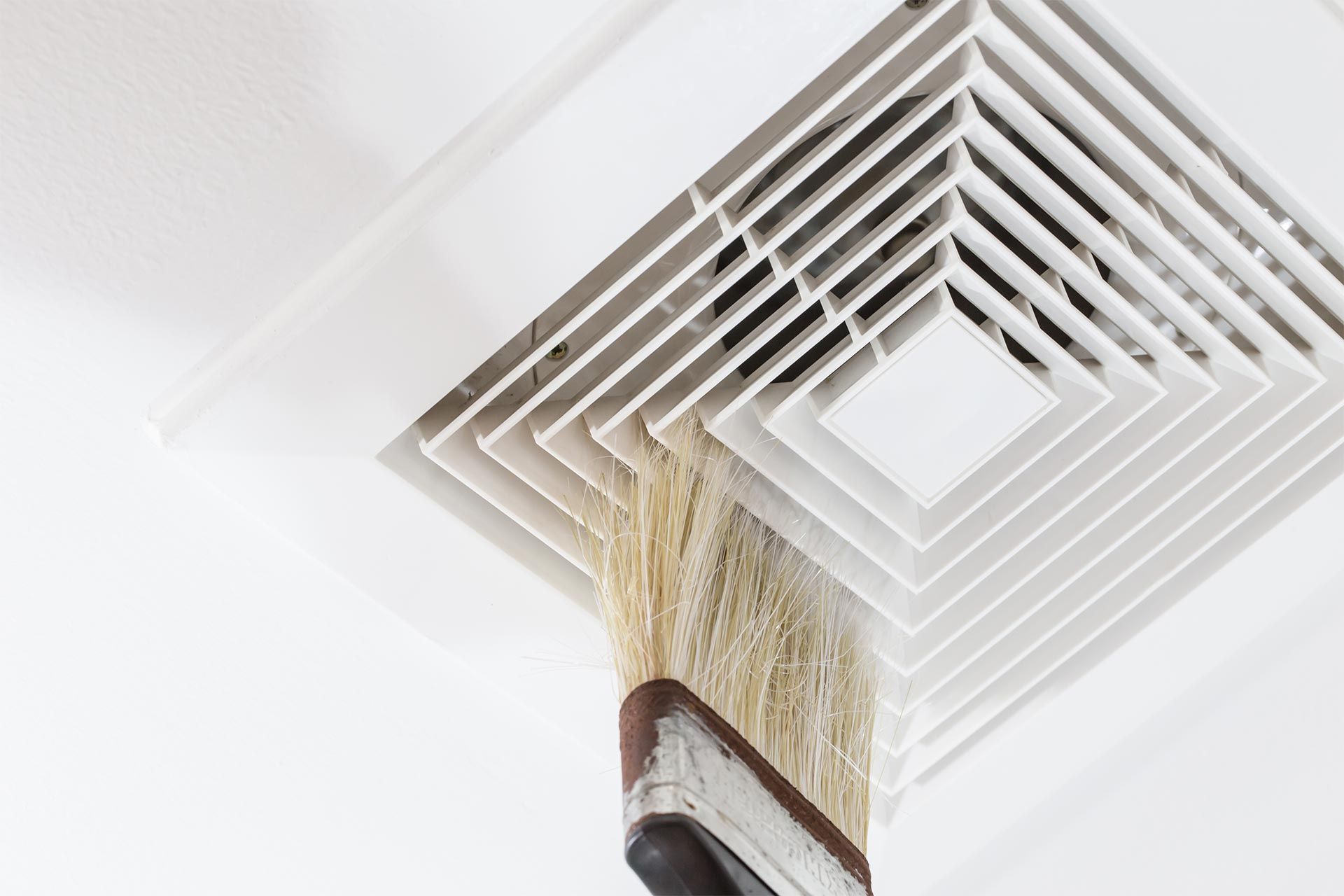 A person is cleaning a vent with a broom