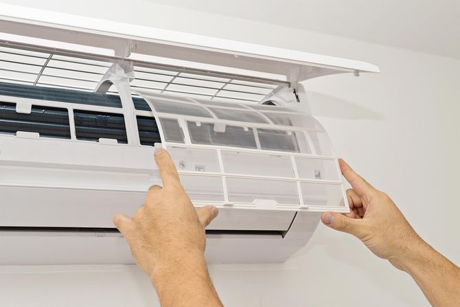 A person is cleaning the filter of an air conditioner