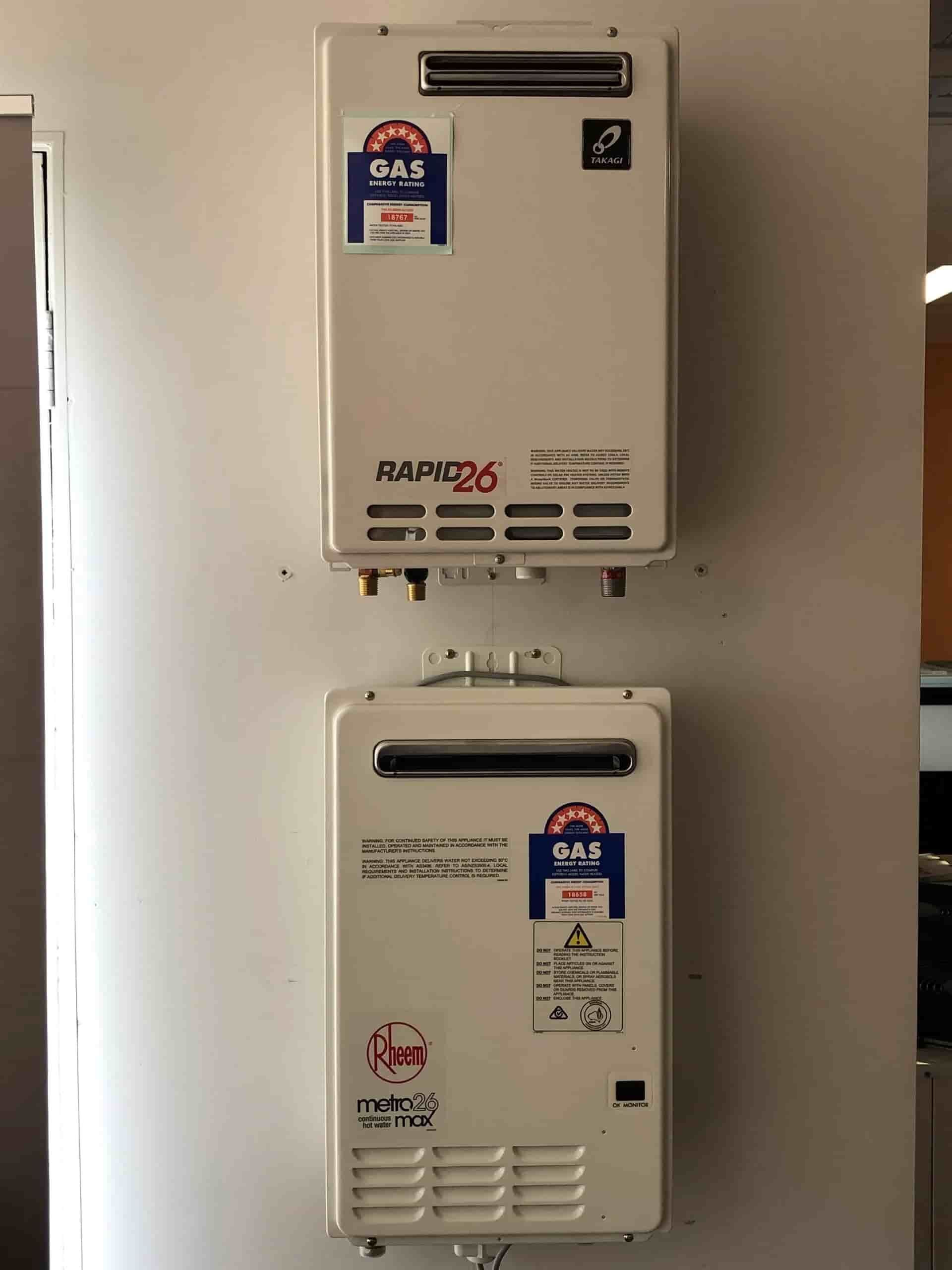 Two Gas Water Heaters Are Hanging on a White Wall — BJ Heating & Cooling in Beechworth, VIC
