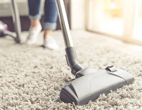 A Woman is Using a Vacuum Cleaner to Clean a Carpet — BJ Heating & Cooling in South Albury, NSW