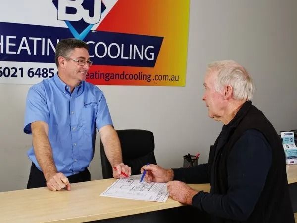 Two Men Are Talking in Front of a Sign That Says Heating and Cooling — BJ Heating & Cooling in South Albury, NSW