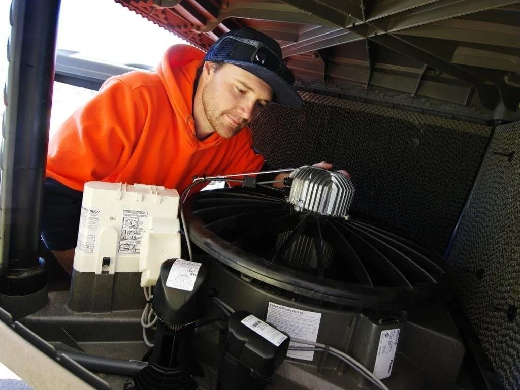 A Man in an Orange Hoodie is Working on a Speaker — BJ Heating & Cooling in Corowa, NSW
