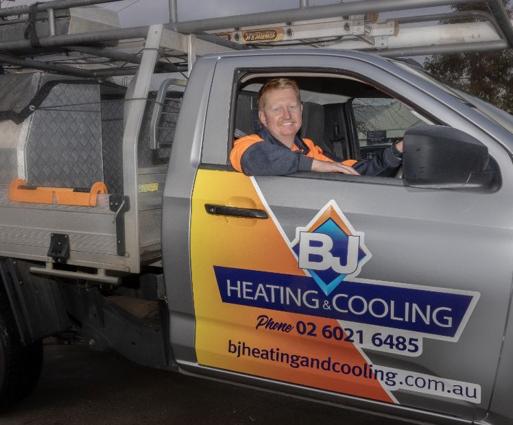A Man is Sitting in the Driver 's Seat of a Bj Heating and Cooling Truck — BJ Heating & Cooling in South Albury, NSW