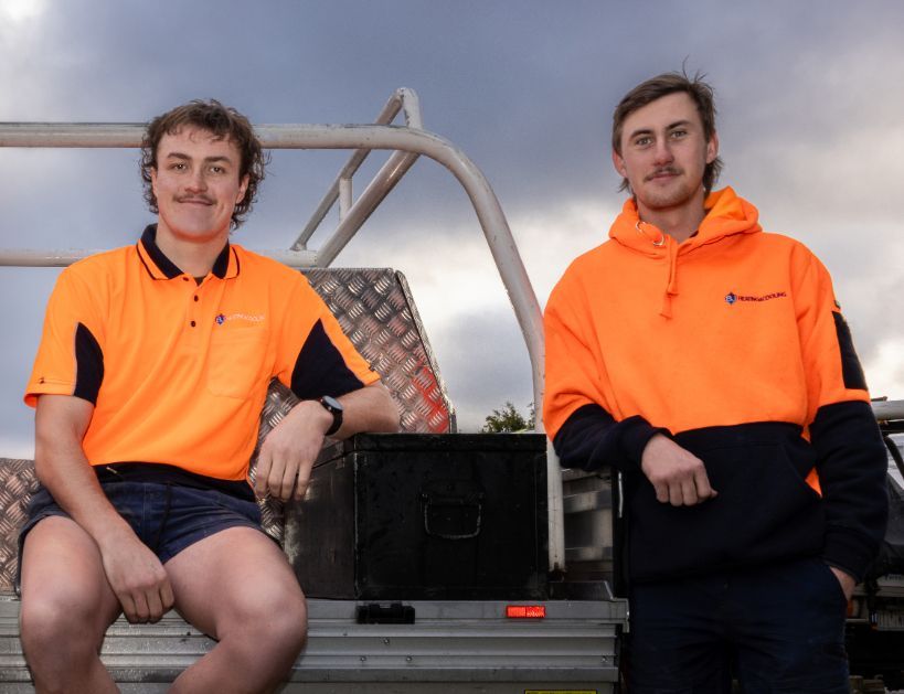 Two Men in Orange Shirts Are Sitting on the Back of a Truck — BJ Heating & Cooling in South Albury, NSW