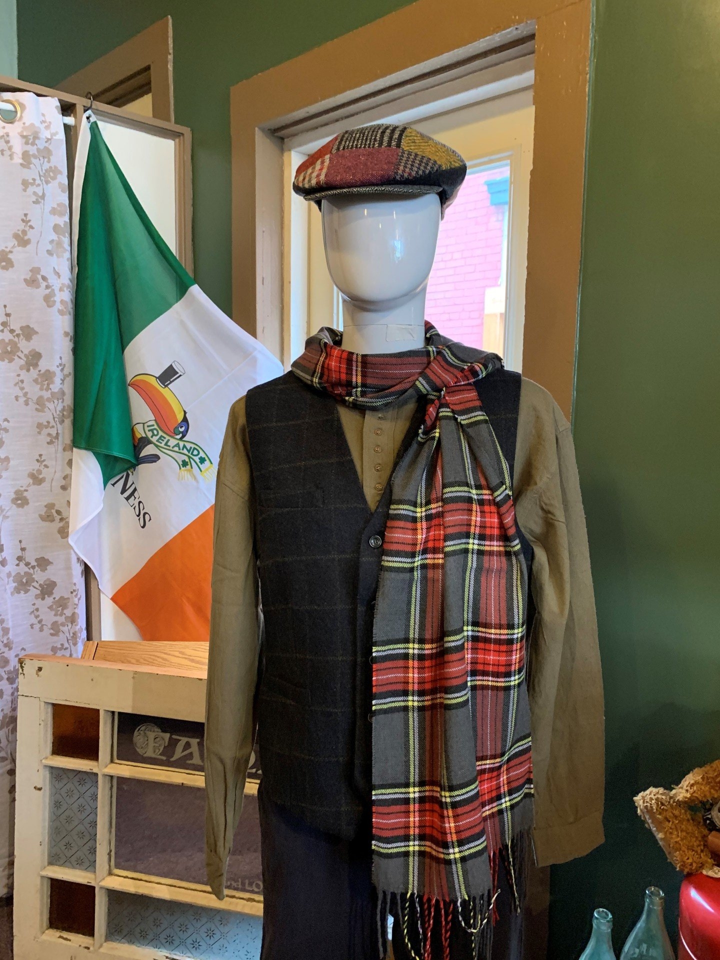 a mannequin wearing a hat and scarf is standing in front of an irish flag .