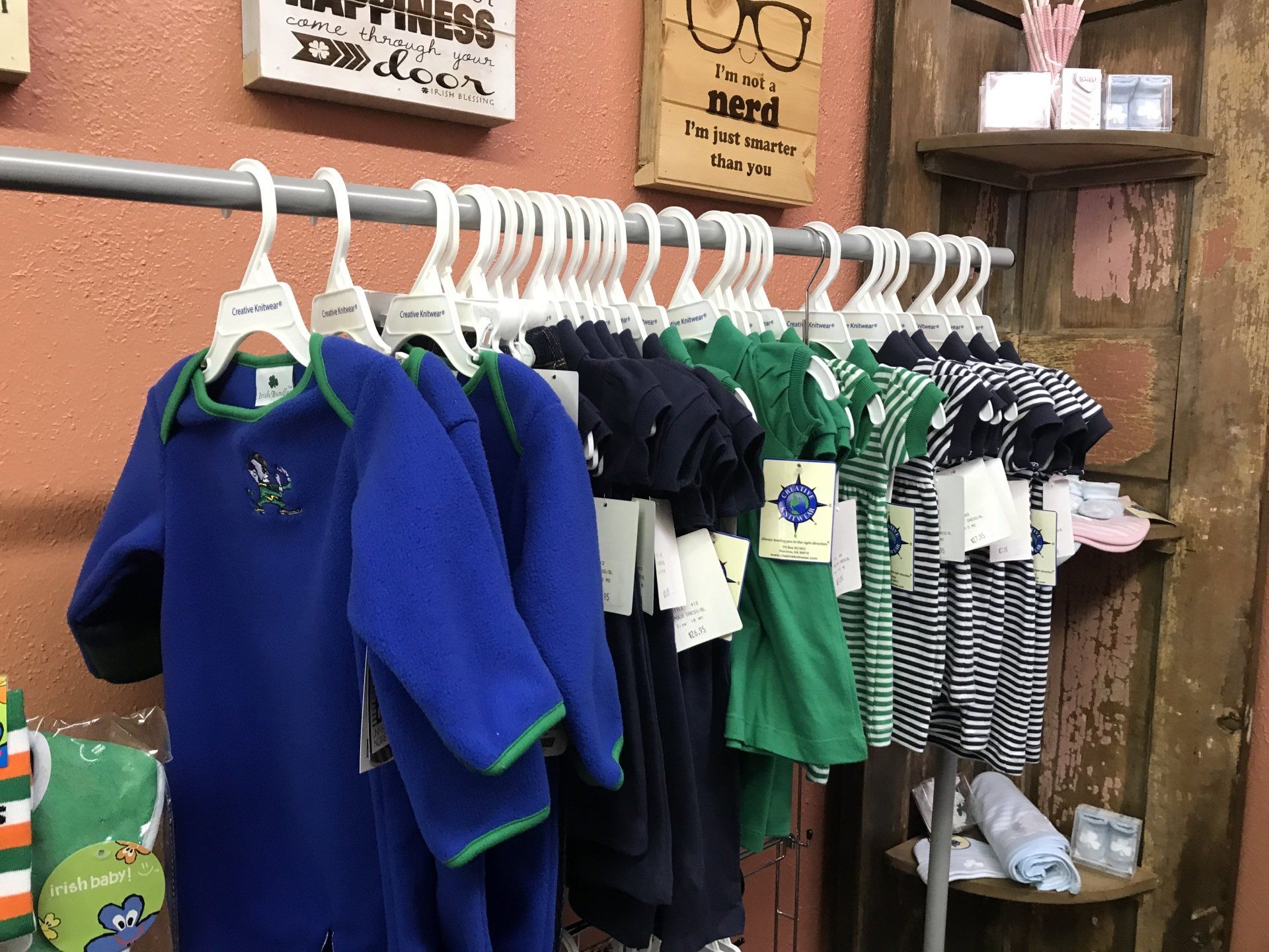 a row of baby clothes hanging on a rack in a store .