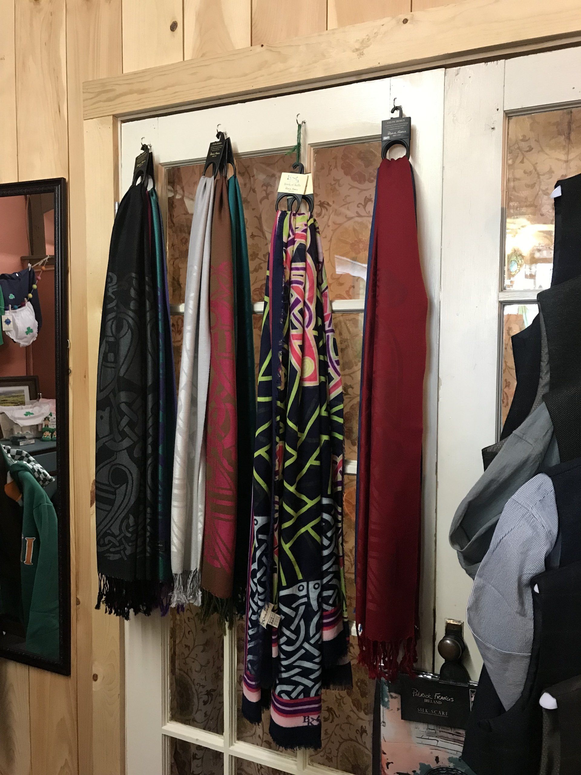 a bunch of scarves are hanging on a rack in a closet .