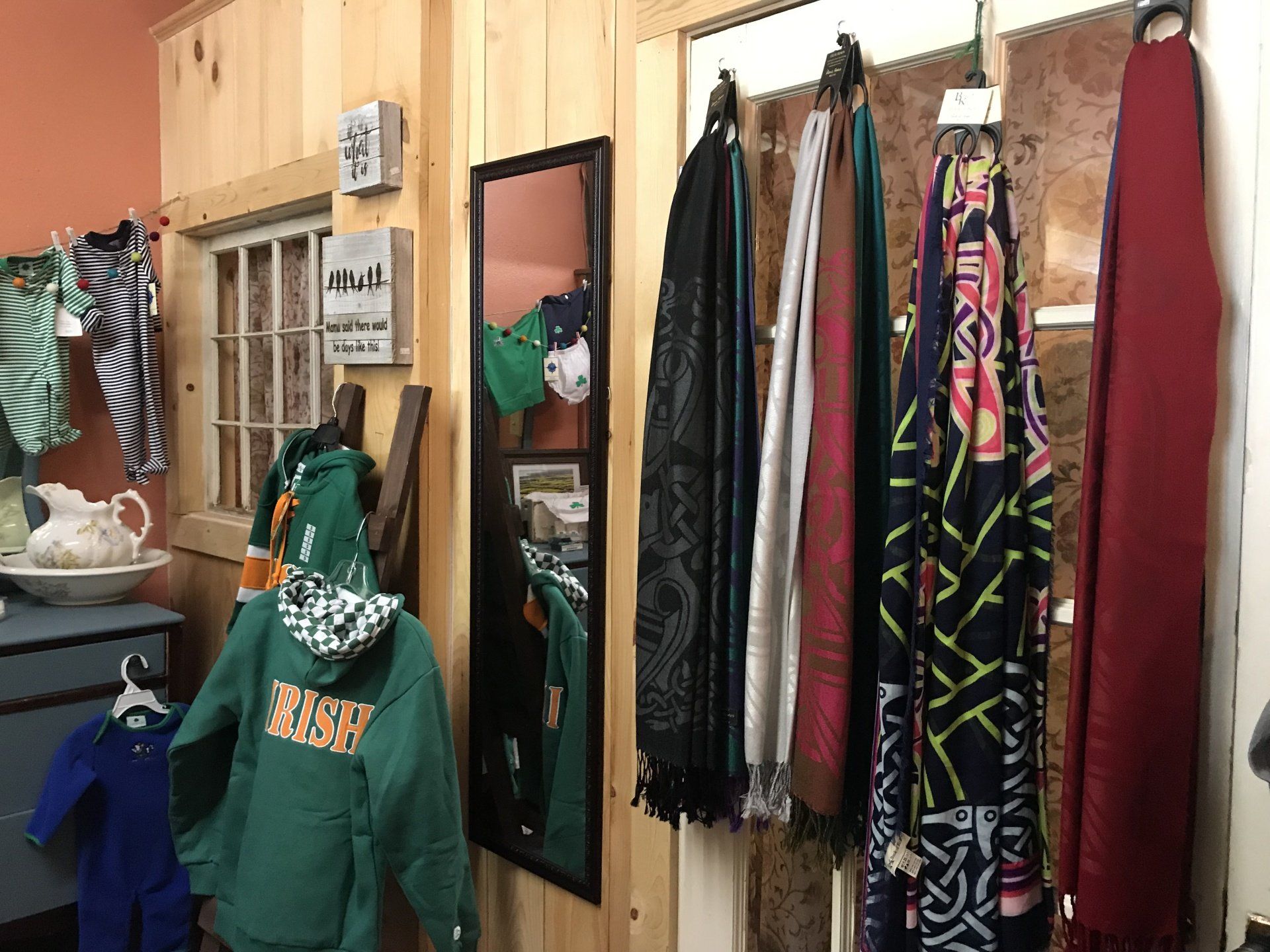 a room with clothes hanging on a wall and a mirror .