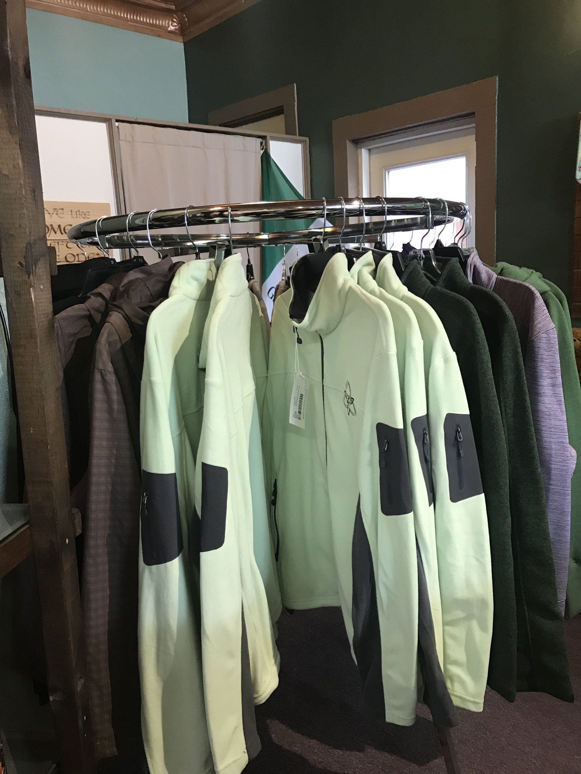 a bunch of jackets are hanging on a rack in a room