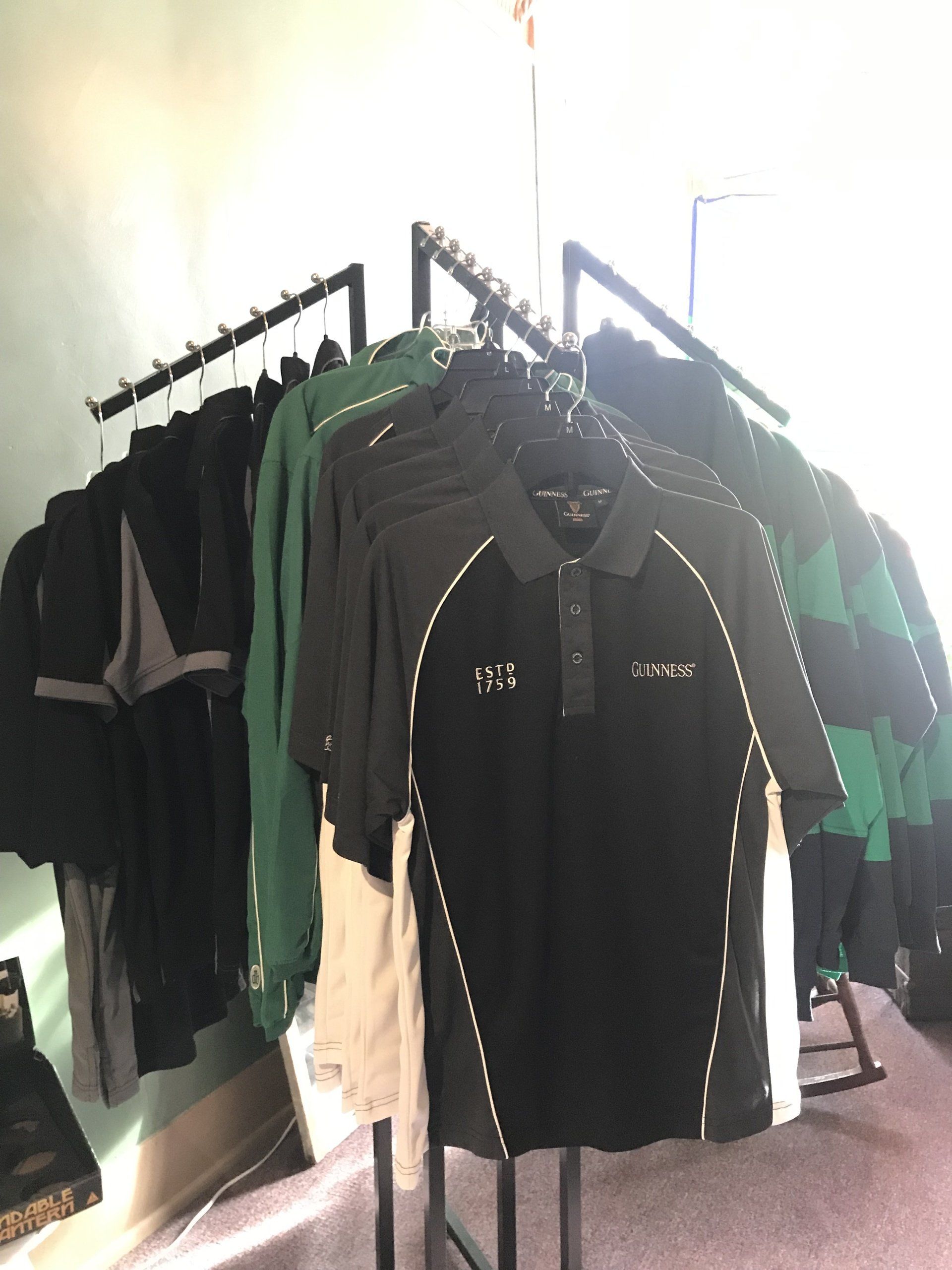 a bunch of shirts are hanging on a rack in a room