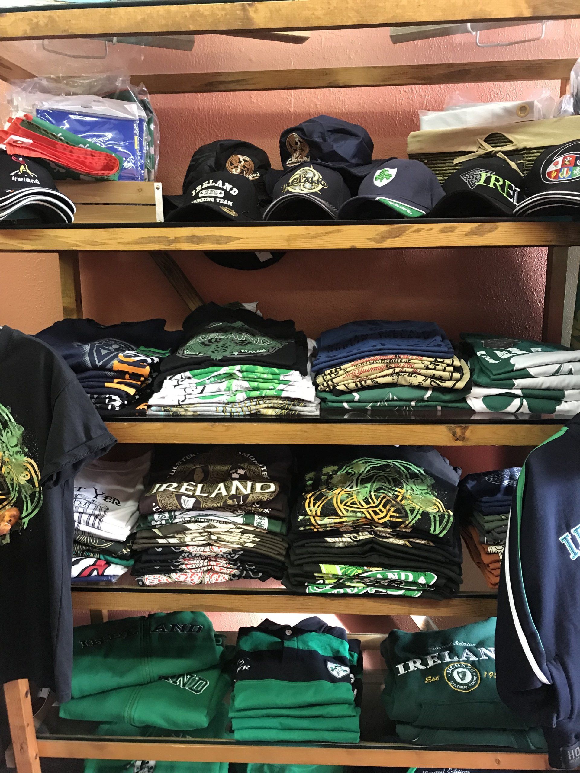a shelf filled with lots of green shirts and hats .