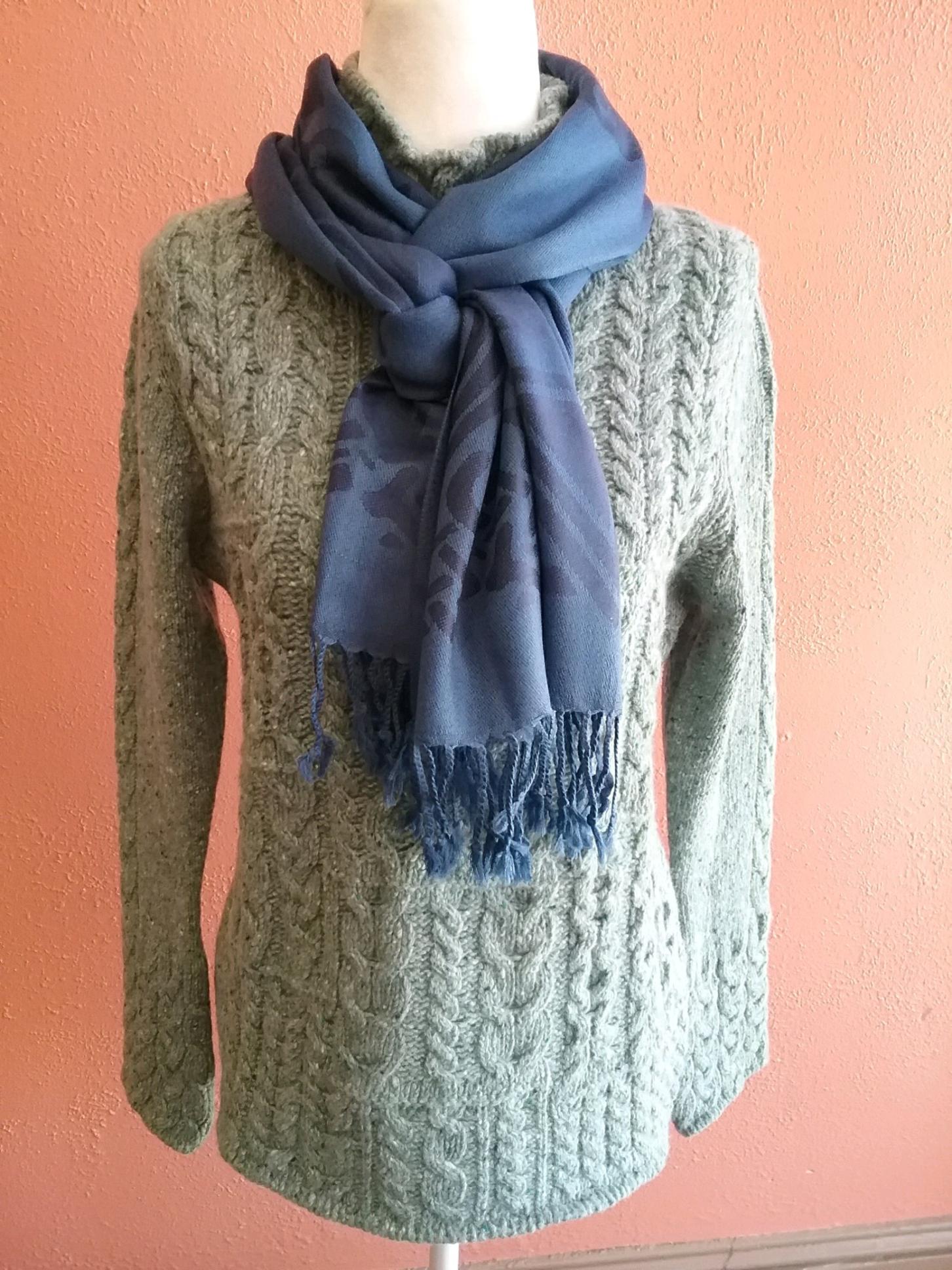 a mannequin wearing a green sweater and a blue scarf .