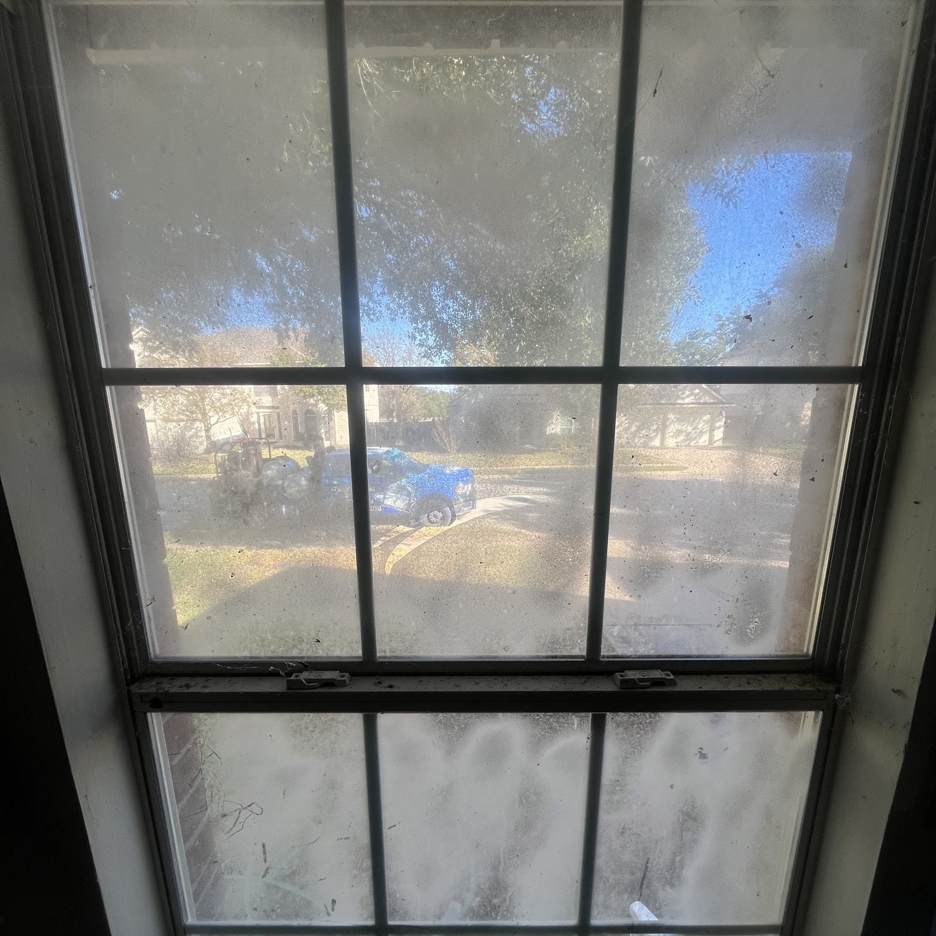 a dirty window with a view of a house and trees