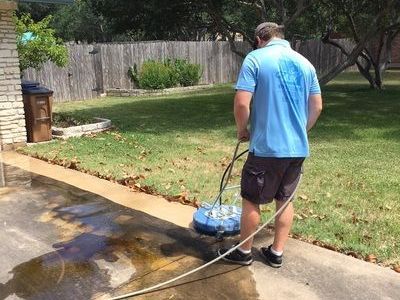 a man is cleaning a driveway with a pressure washer.