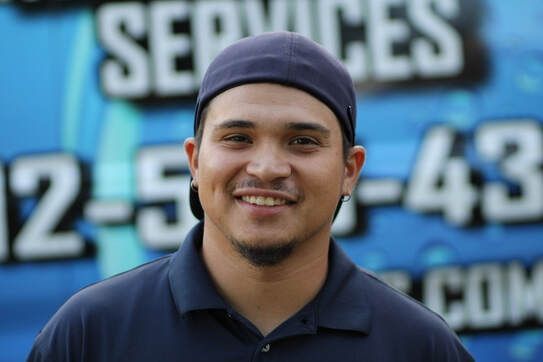 a man wearing a purple hat and a blue shirt is smiling in front of a service truck .