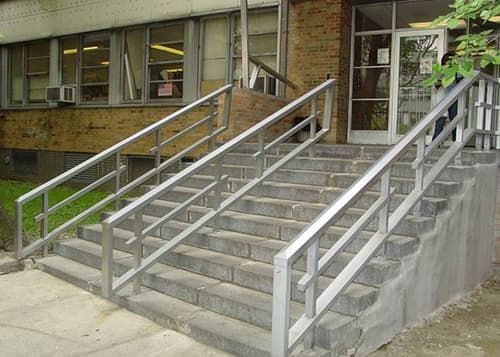 A set of stairs with a metal railing leading up to a building.