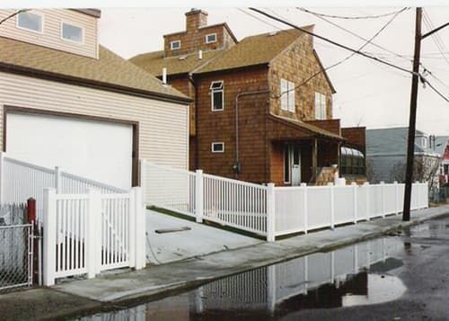 A house with a white fence and a garage next to it