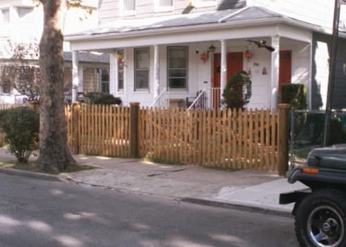 A jeep is parked in front of a house with a picket fence