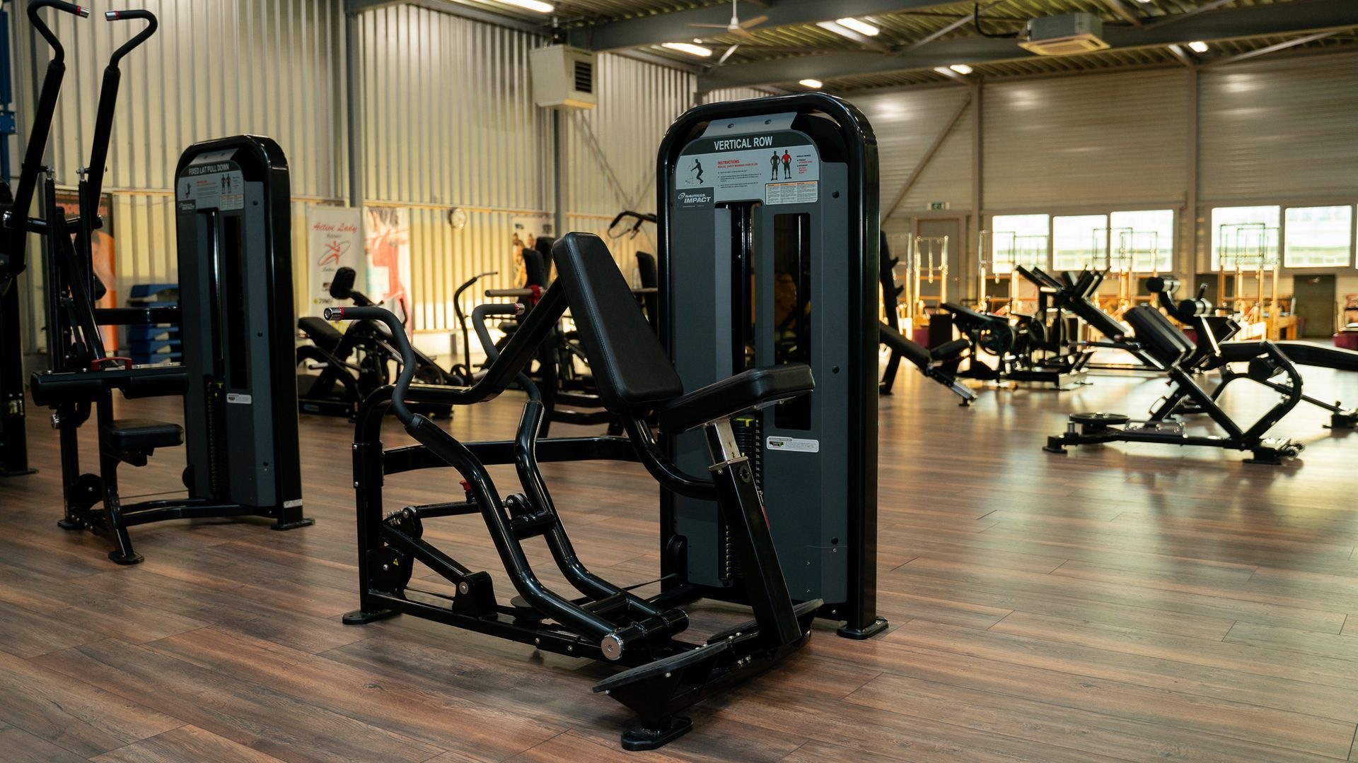 Een sportschool met veel fitnessapparatuur op de vloer.