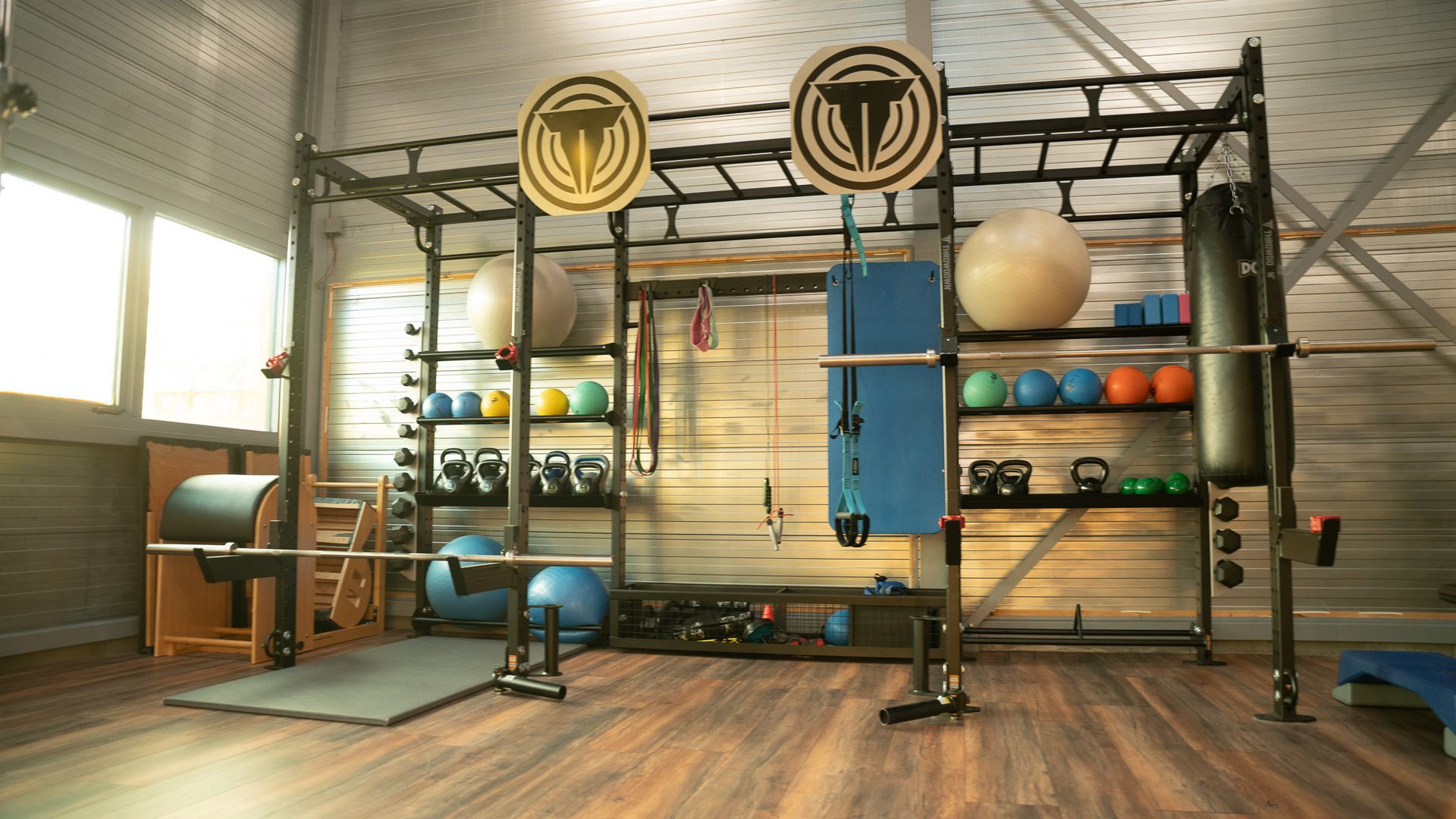 Een sportschool met veel apparatuur en een houten vloer.