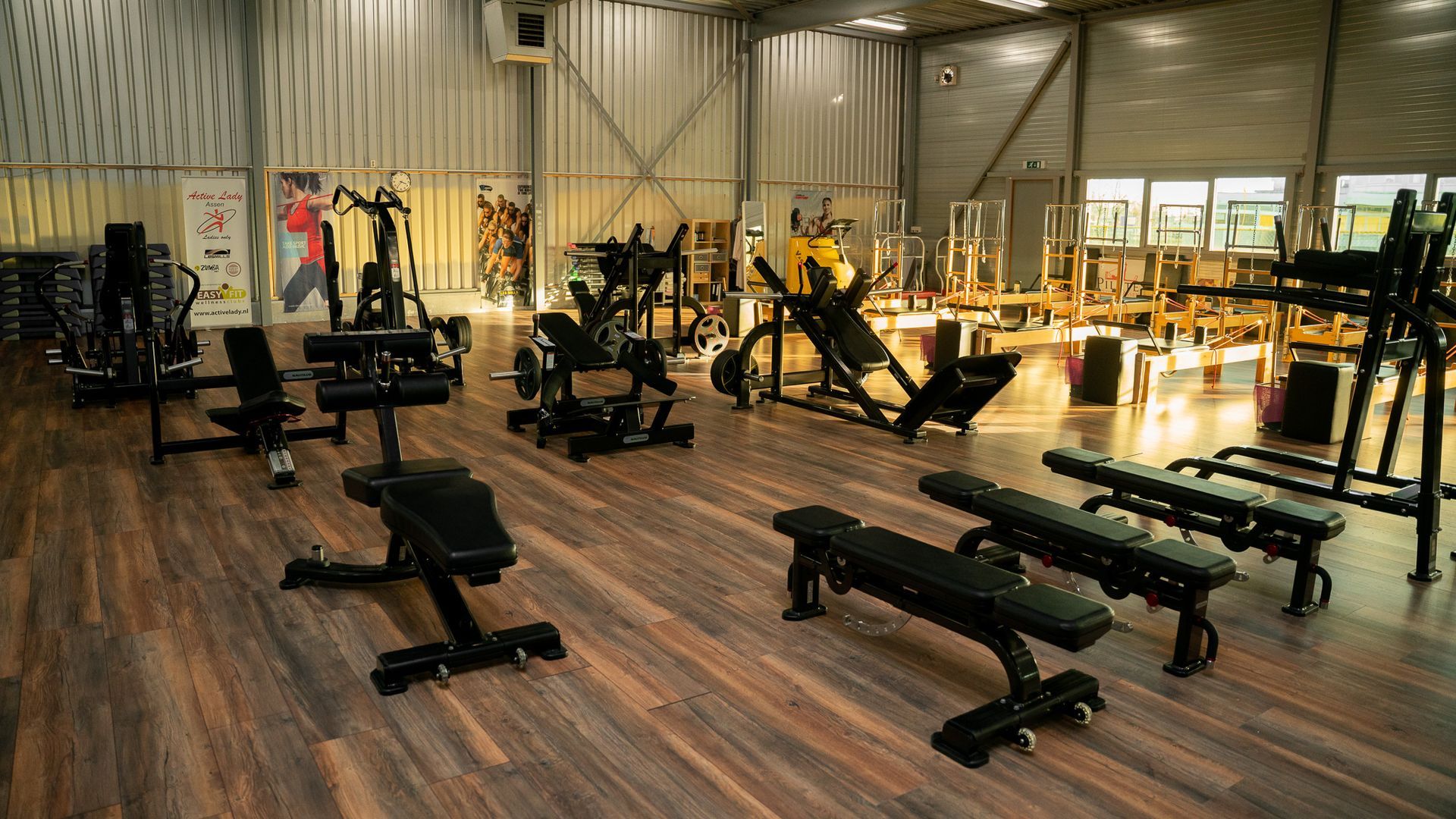 Een sportschool vol met fitnessapparatuur en banken.