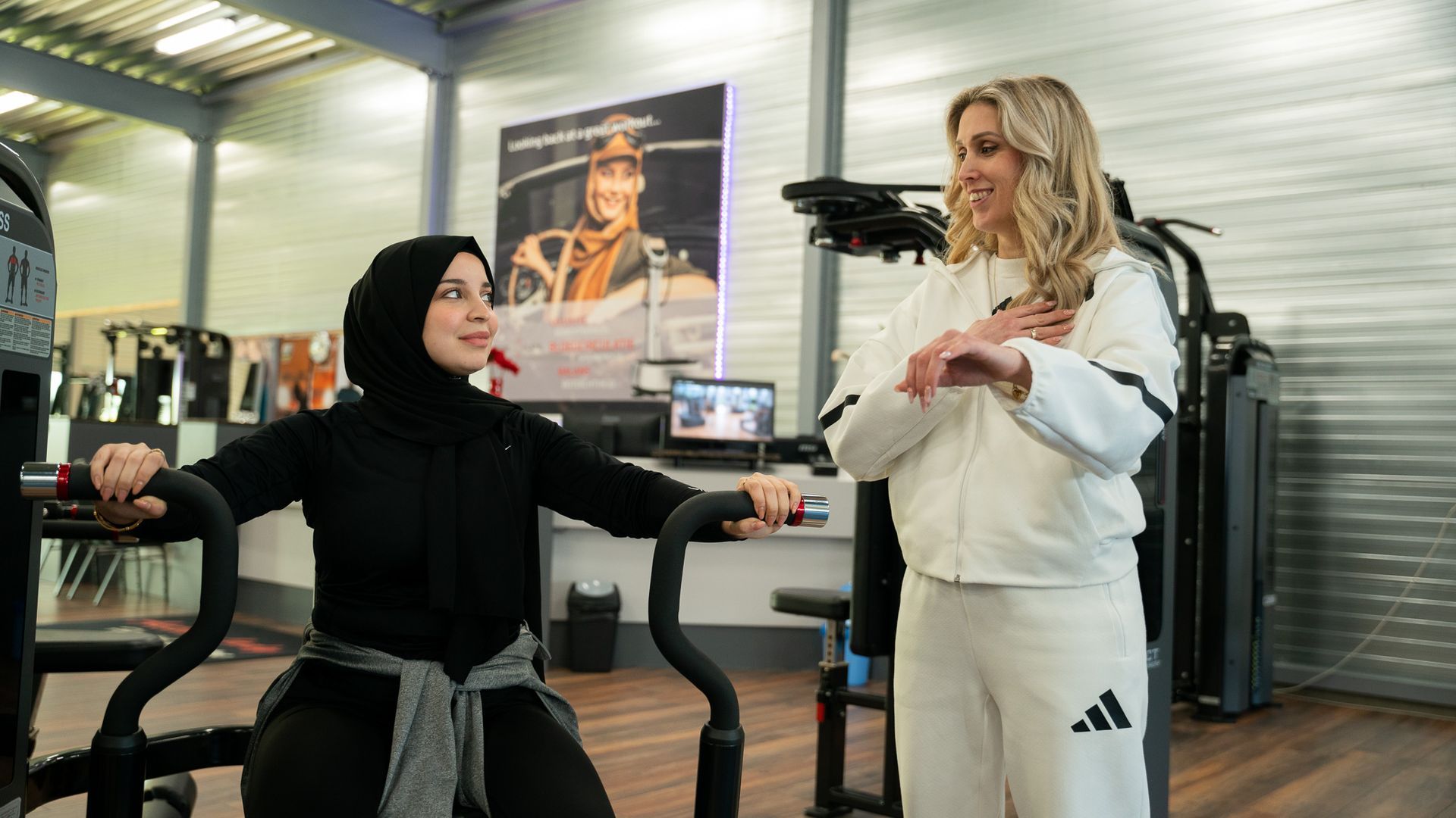 Twee vrouwen staan naast elkaar in een sportschool. Een van de vrouwen draagt een hijab.