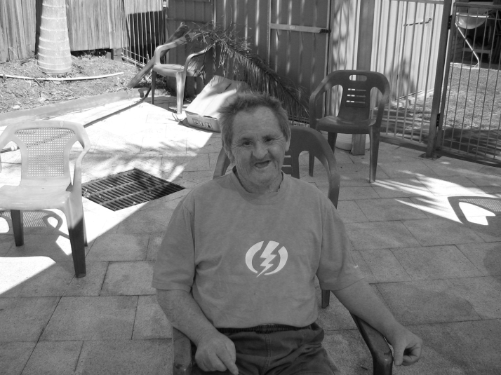 Black and white photo of a male client smiling, sitting outside  