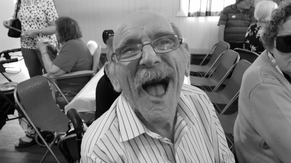 Black and white photo of a male client smiling, sitting inside 