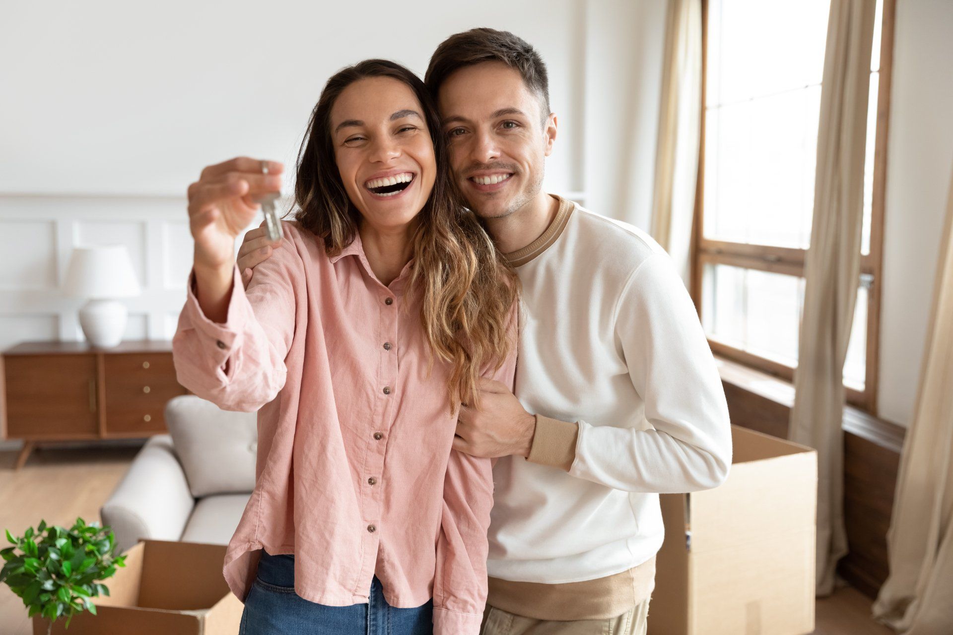 Happy young family couple holding key to new home on moving day concep