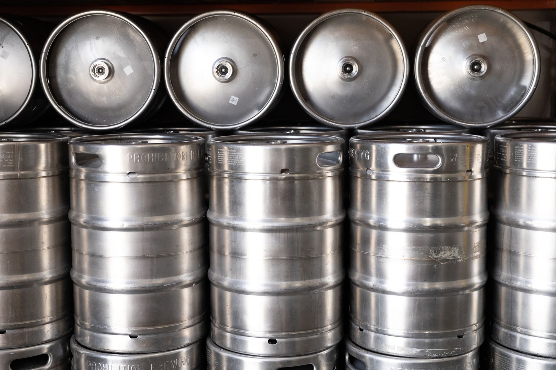 A row of stainless steel kegs stacked on top of each other.