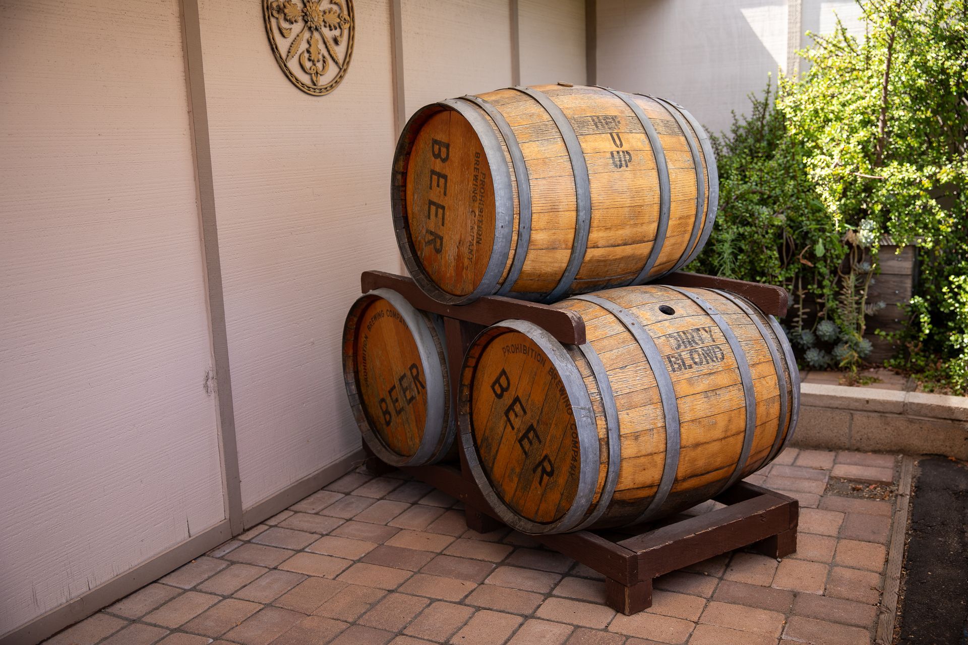 Three beer barrels are stacked on top of each other on a brick patio.