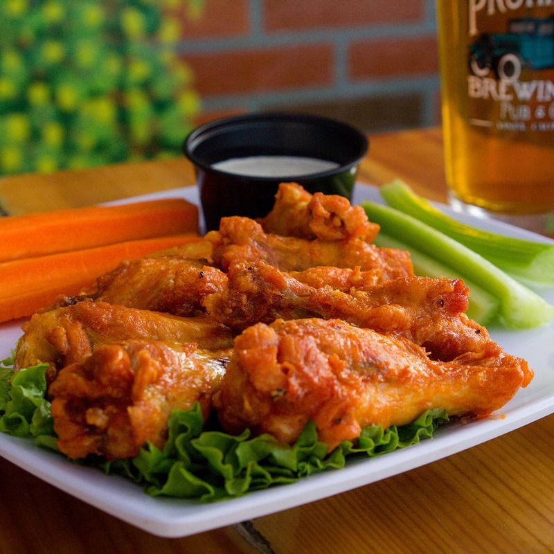 A white plate topped with chicken wings celery and carrots