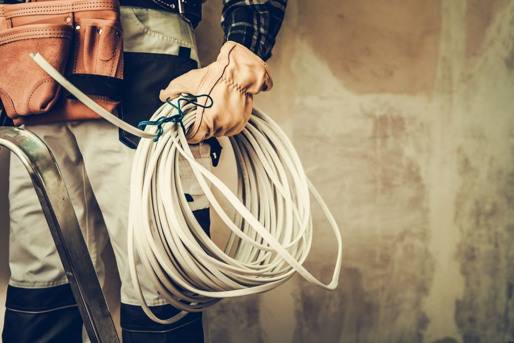 A man is holding a roll of wire in his hands.