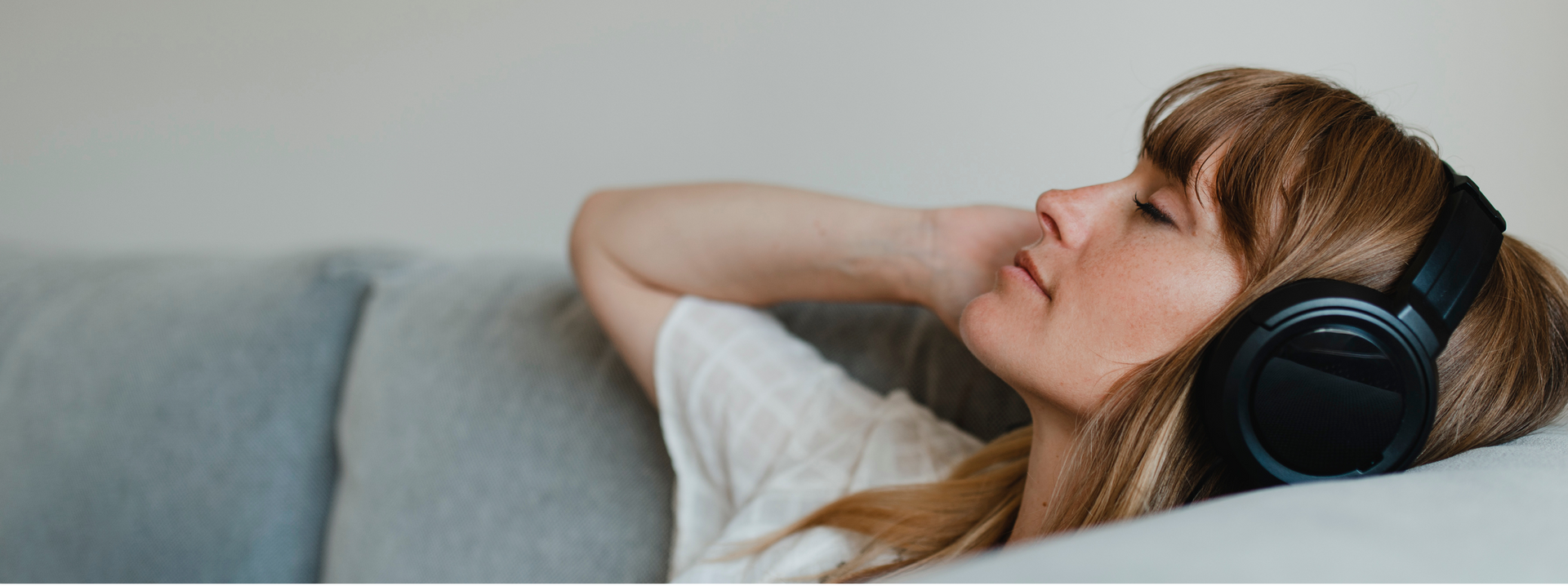 A woman is sitting on a couch wearing headphones.