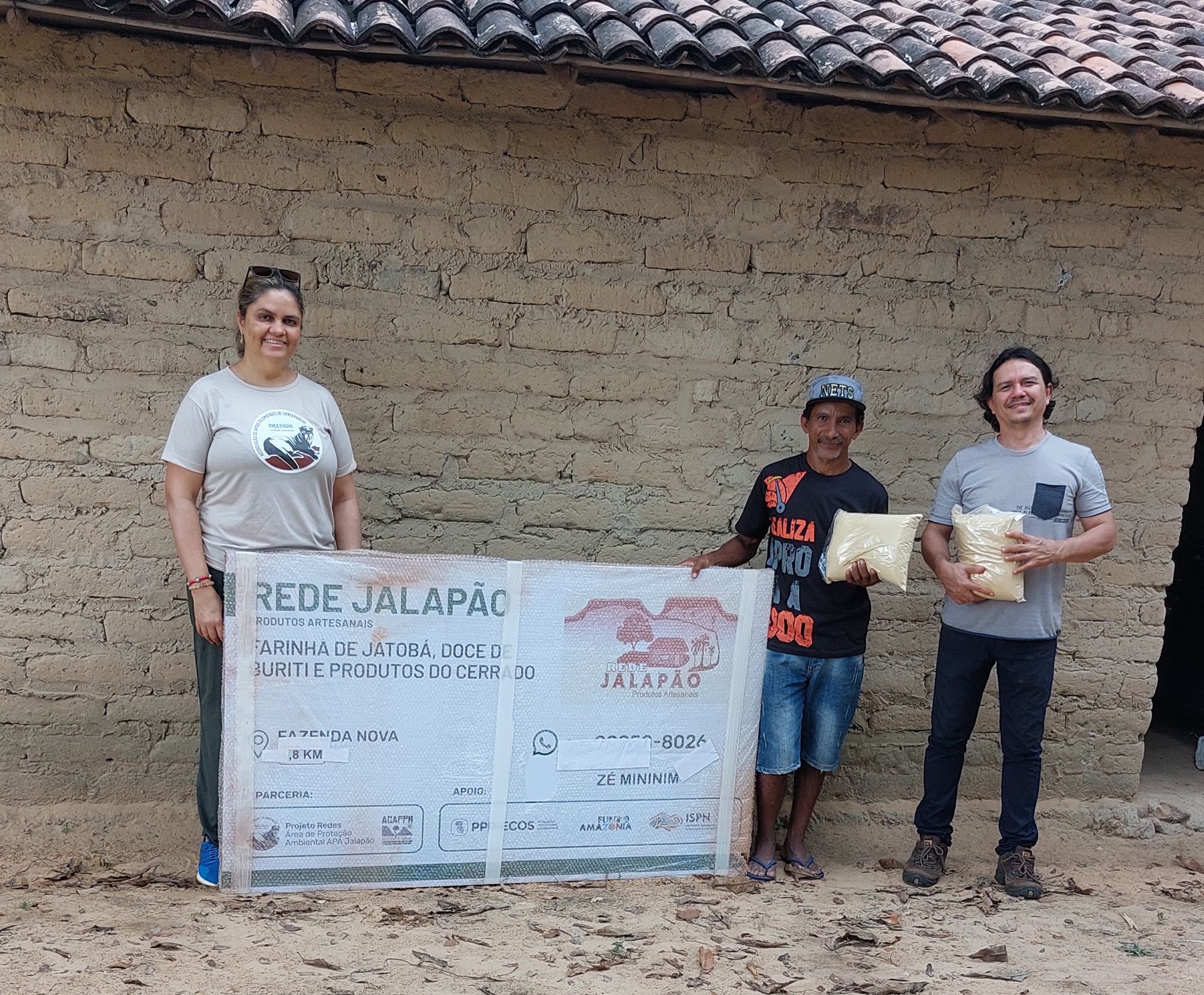 Três pessoas em pé em frente a um cheque que diz rede jalapão