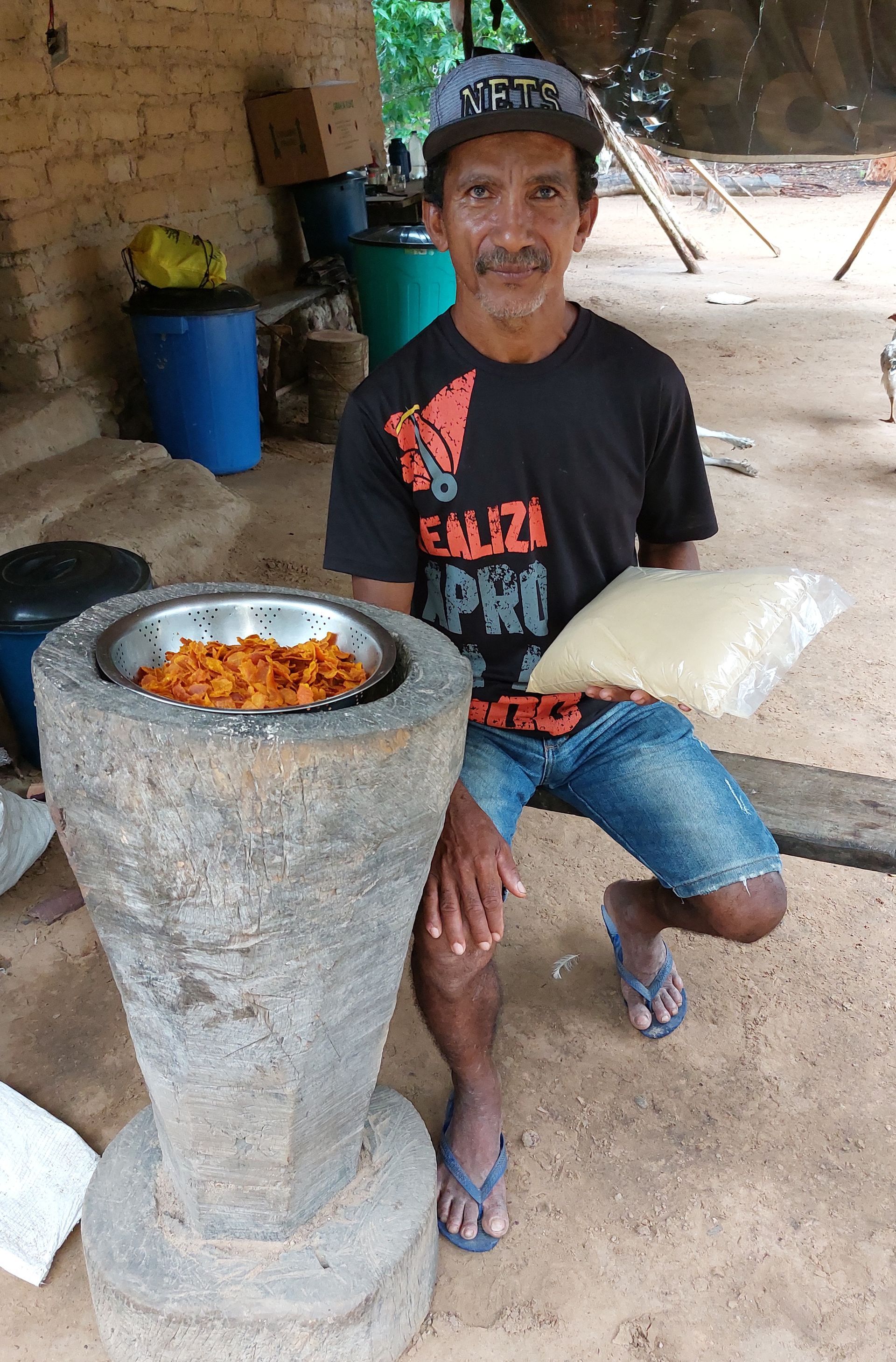 Um homem está sentado ao lado de uma tigela de comida e segurando um saco de arroz.
