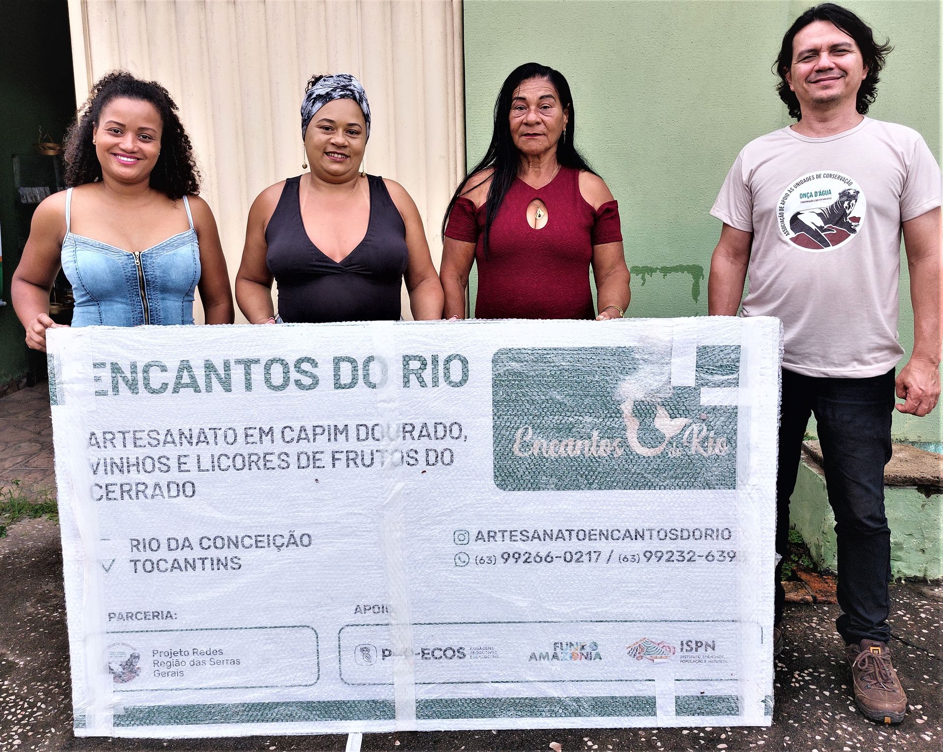 Um grupo de pessoas segurando uma placa que diz encantos do rio