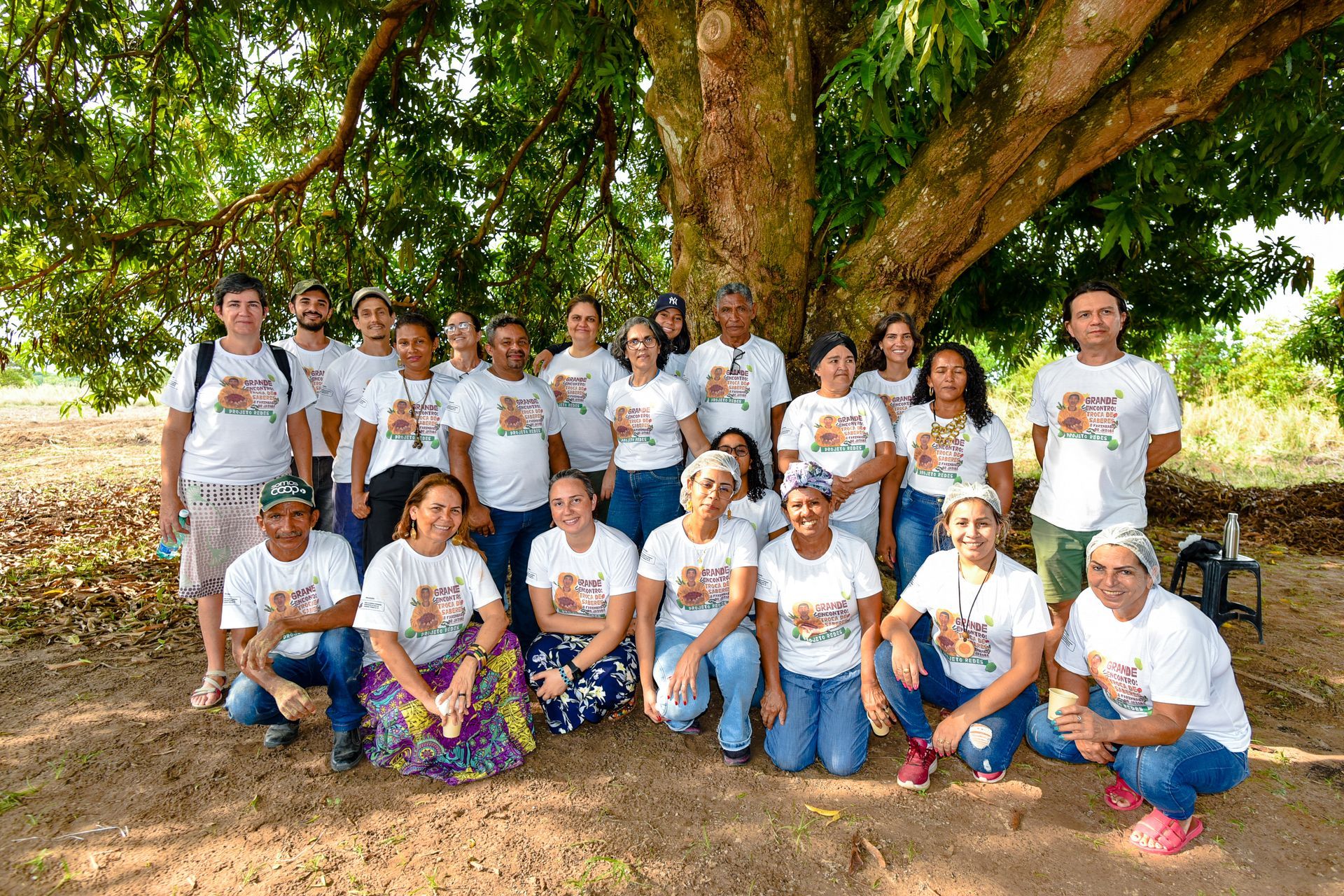 Um grupo de pessoas está posando para uma foto debaixo de uma árvore.