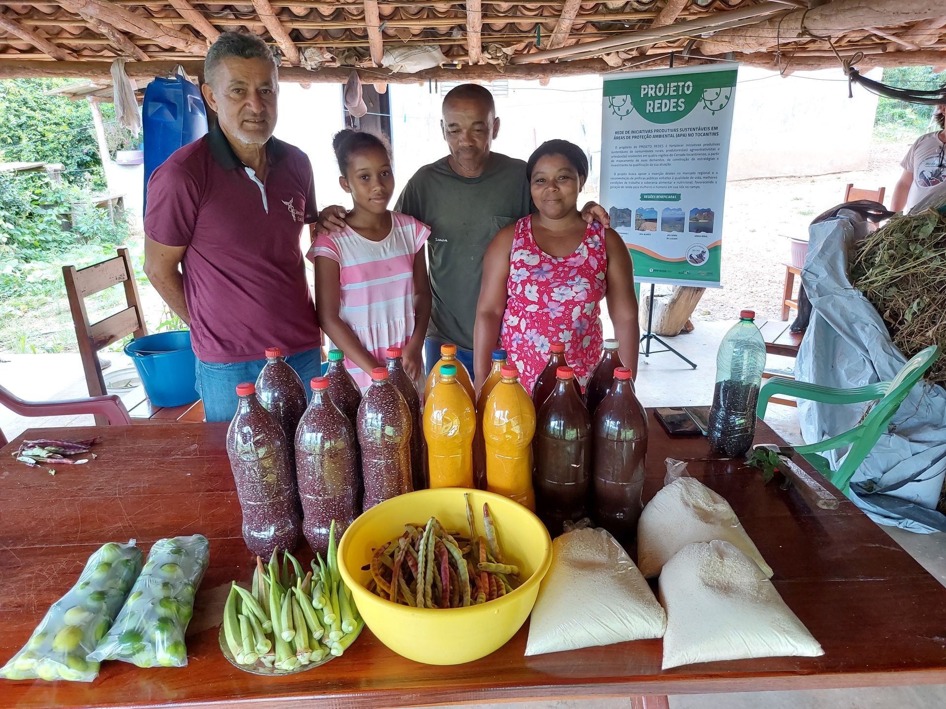 Um grupo de pessoas está em pé ao redor de uma mesa com garrafas de comida.