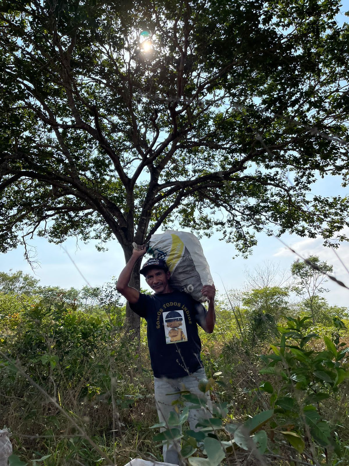 Um homem está carregando uma grande sacola na cabeça em um campo.