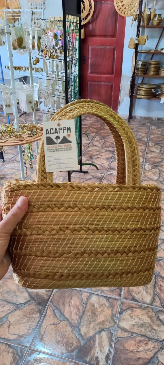Uma pessoa está segurando uma bolsa de vime em uma loja.