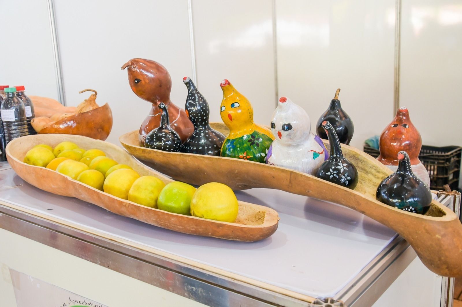 Uma mesa com uma tigela de frutas e uma tigela de esculturas sobre ela.