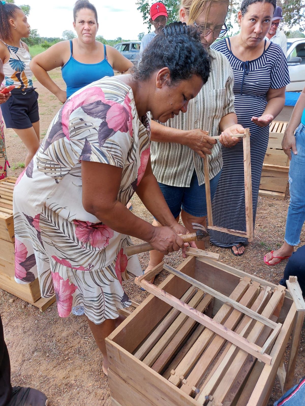Uma mulher com um vestido floral está trabalhando em uma caixa de madeira.