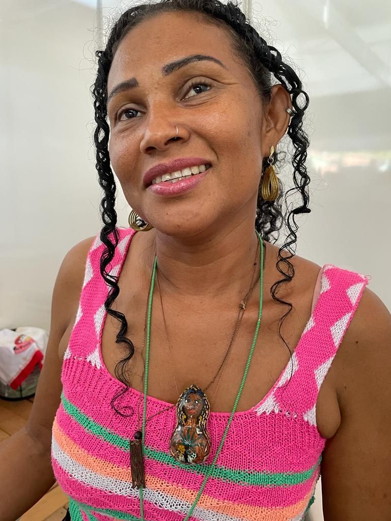 Uma mulher vestindo uma blusa rosa e brincos está sorrindo para a câmera.